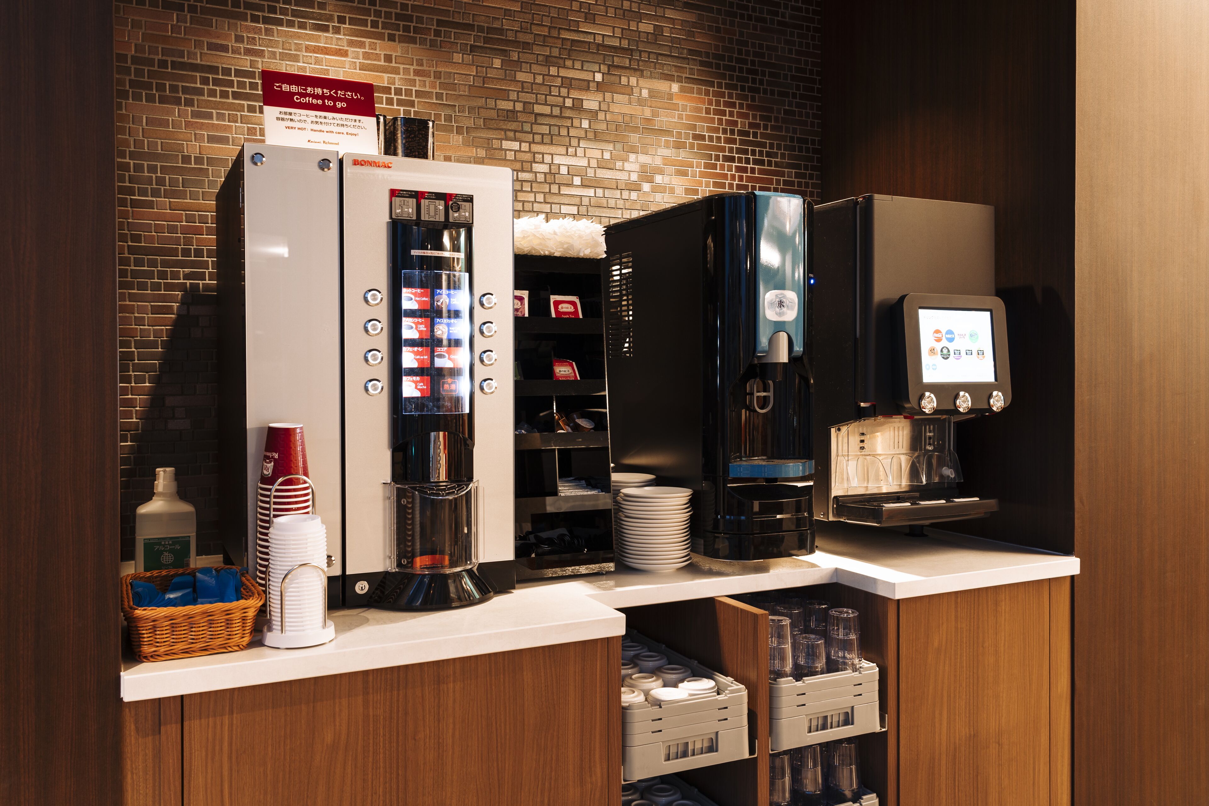 A coffee station with a coffee machine, a beverage dispenser, and a sign indicating coffee is available.
