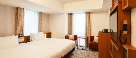 A hotel room with two large beds, a small table, a TV, and a red armchair.