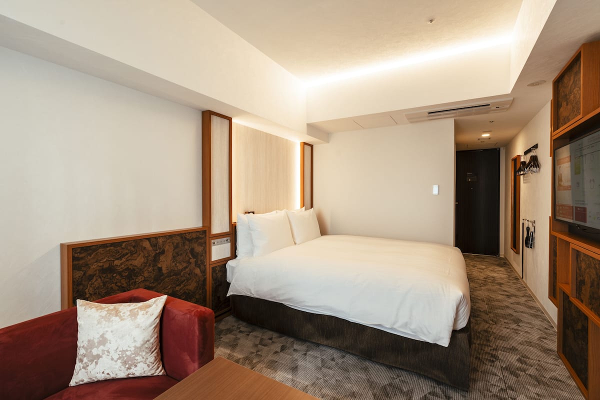 A hotel room with a large bed, a red sofa, and a wooden headboard.