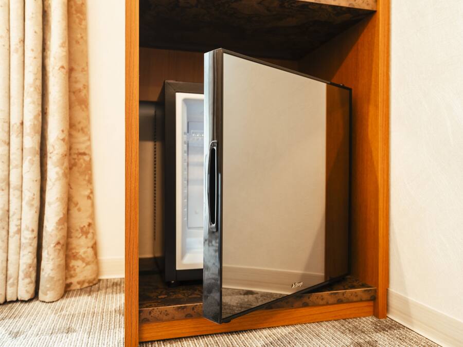 Un refrigerador compacto en un espacio reducido con base de madera y puerta blanca.
