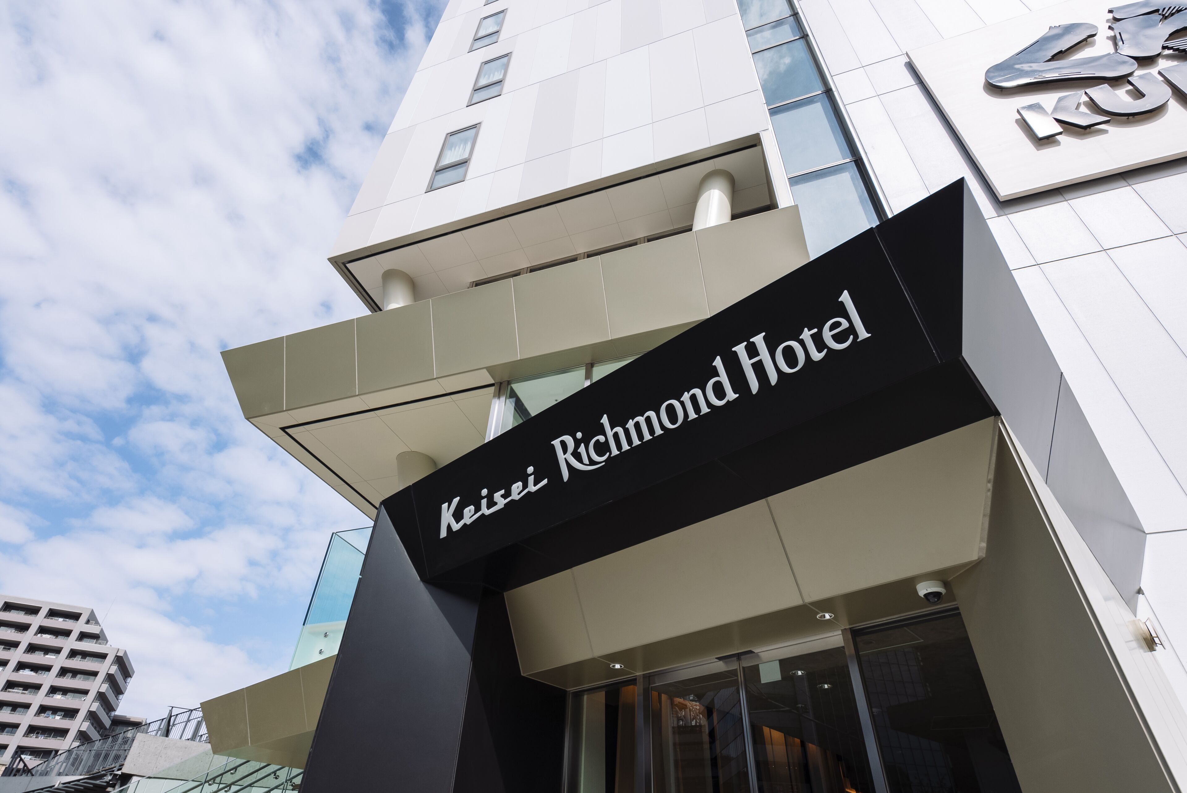 Das moderne Äußere des Keisei Richmond Hotels mit markanter Beschilderung und Glasfassade.