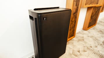 A black refrigerator in a room with a wooden cabinet and a patterned carpet.