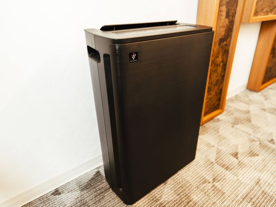 A black refrigerator in a room with a wooden cabinet and a patterned carpet.