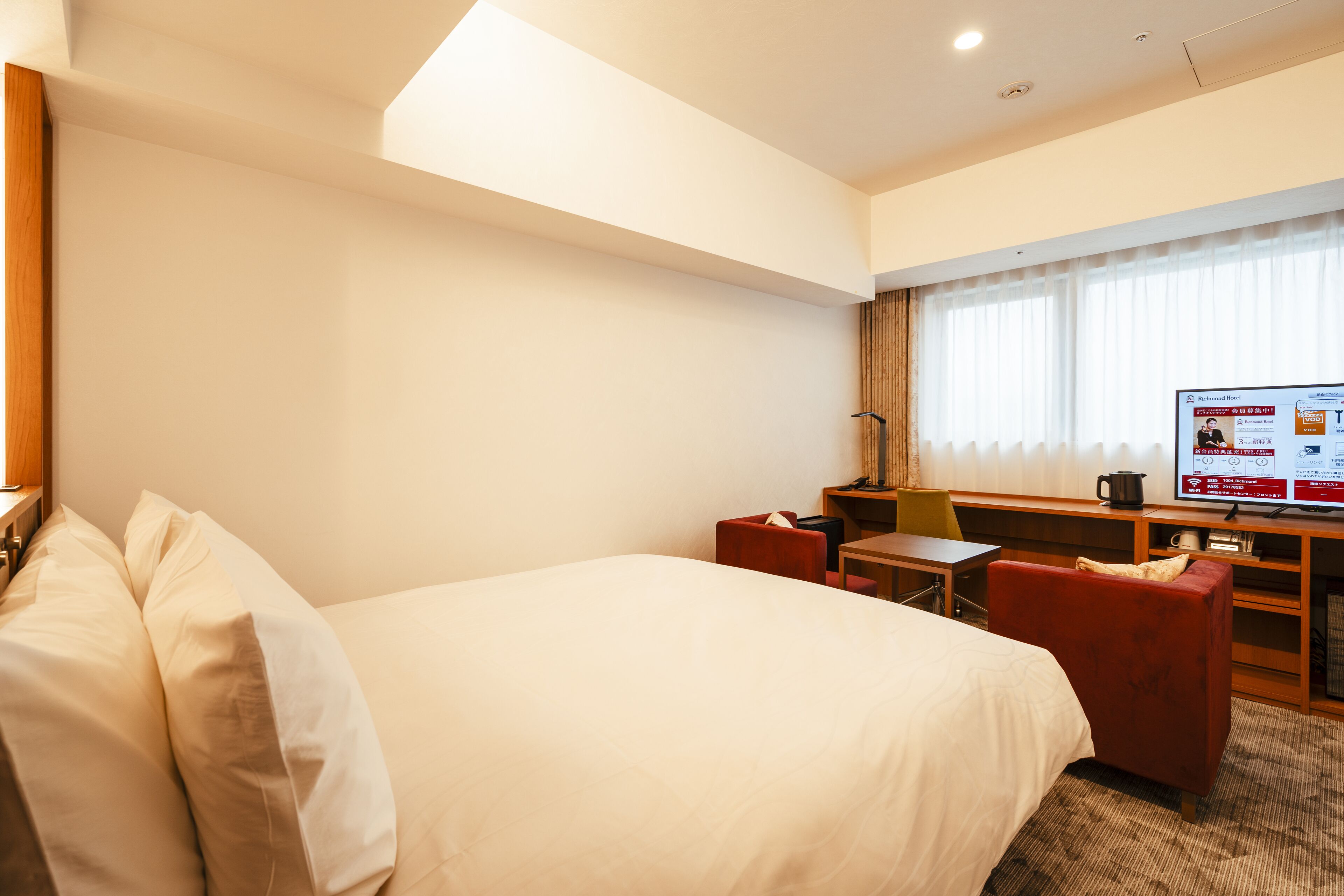 Ein Hotelzimmer mit einem großen Bett, einem Schreibtisch, einem Sessel und einem Fernseher.