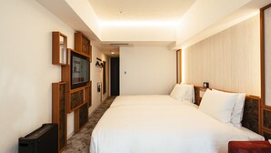 A hotel room with a large bed, a wooden headboard, a small table, and a TV on a wooden stand.