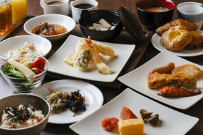 Una variedad de platillos, incluyendo sushi, tempura y cruasanes, sobre una mesa de madera.