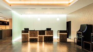 A modern reception area with a marble counter, pendant lighting, and a digital screen.