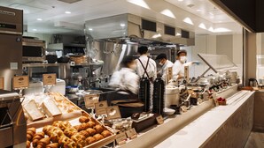 A commercial kitchen with stainless steel appliances, a buffet counter with various food items, and staff in uniforms.