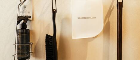 A wall-mounted cleaning tool, a black brush, and a white cloth labeled "SHOE SHINE CLOTH".