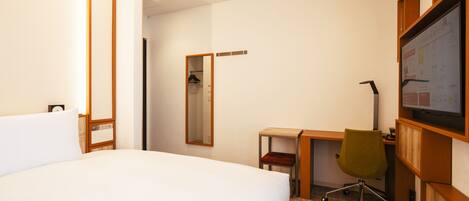 Habitación de hotel con una cama grande, un escritorio con silla, un espejo y un televisor en la pared.