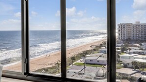 Vista de una playa desde una ventana, con un edificio al fondo.