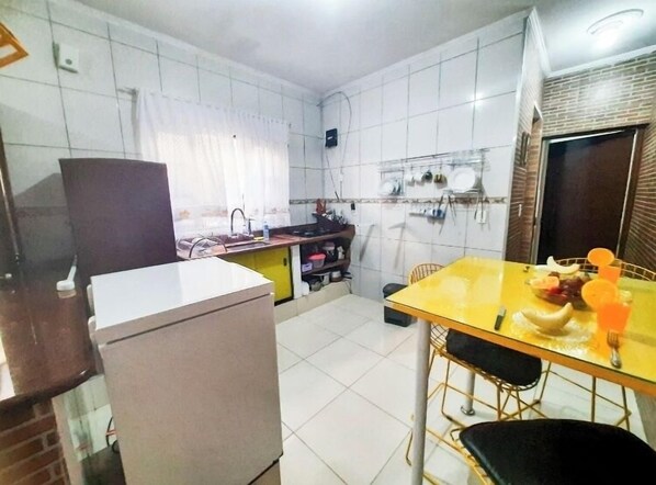 A compact kitchen with a refrigerator, a sink, and a dining table with chairs.