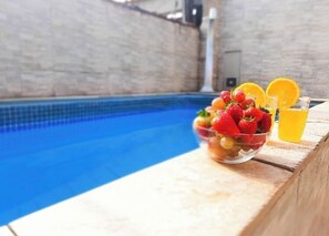 A poolside setting with a bowl of fruit and drinks. - House with a pool near the waterfall (Mongaguá)