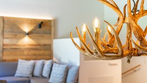 Una sala de estar moderna con una pared de madera, un sofá y una araña con lámparas con forma de asta de ciervo.