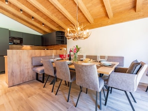 Un comedor moderno con techo de madera, una araña y una mesa de madera dispuesta para seis comensales.