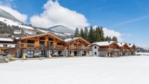 Una hilera de cabañas de madera con balcones, con una imponente montaña nevada al fondo.