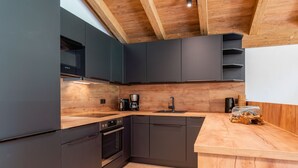 Una cocina moderna con armarios oscuros, encimera de madera y horno empotrado.