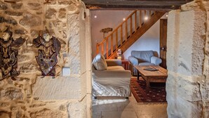 Ein Zimmer mit Steinwänden, einer Holztreppe, einem Sofa und einem Couchtisch.