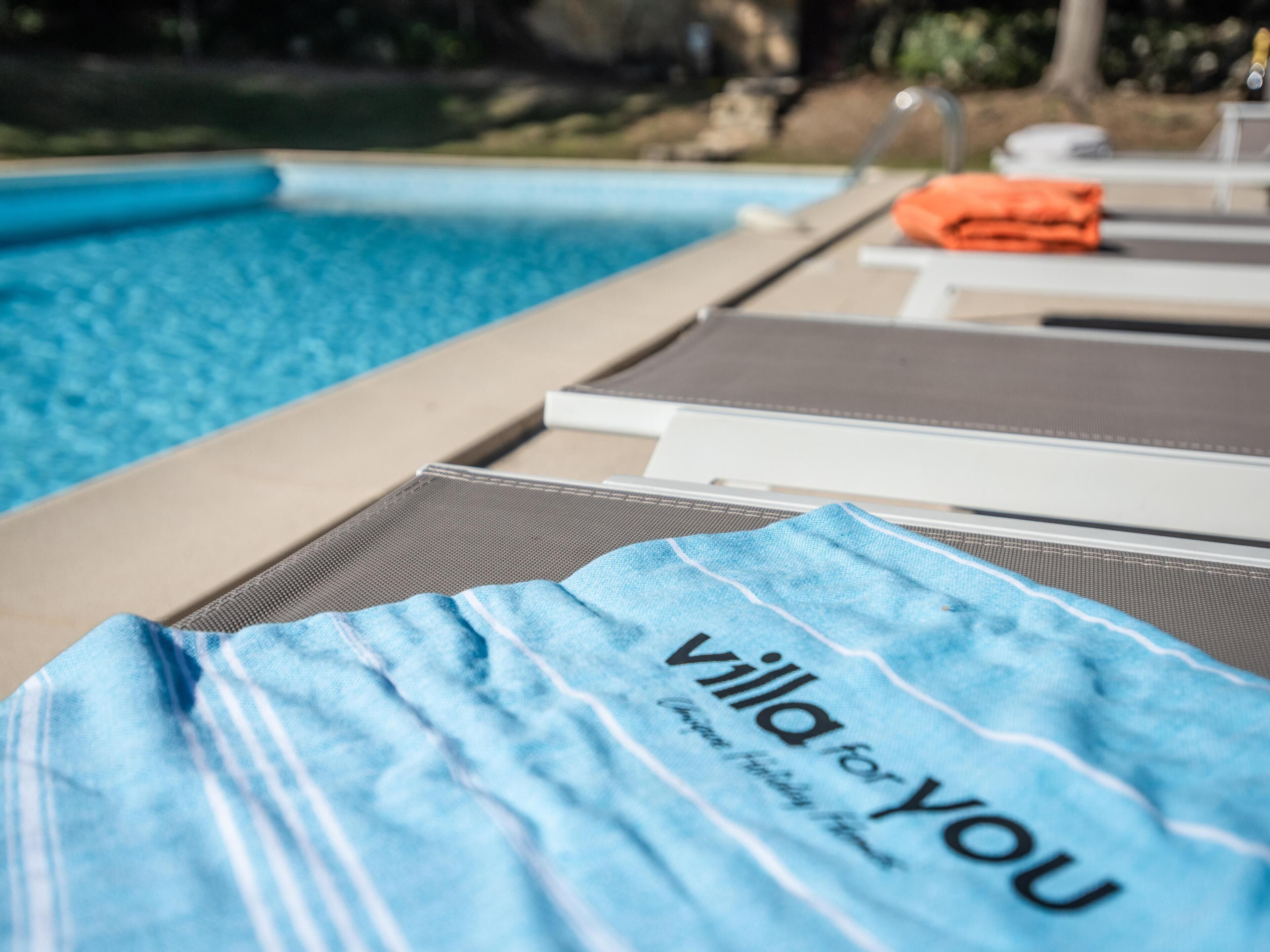 A poolside area with lounge chairs and a towel with text.