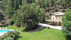 Eine Villa mit Swimmingpool, umgeben von üppiger Vegetation und Hügeln.