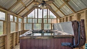 A hot tub in a wooden cabin with large windows and a ceiling fan. - 'Grace Place' Clark House on Farm: Shared Hot Tub! (Clark)