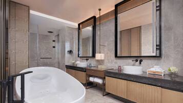 Un baño moderno con una bañera independiente, un espejo grande y un lavamanos con lavabo y toallero.