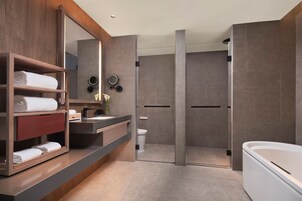 Un baño moderno con tocador de madera, un espejo grande, cabina de ducha con paredes de vidrio y una bañera blanca.