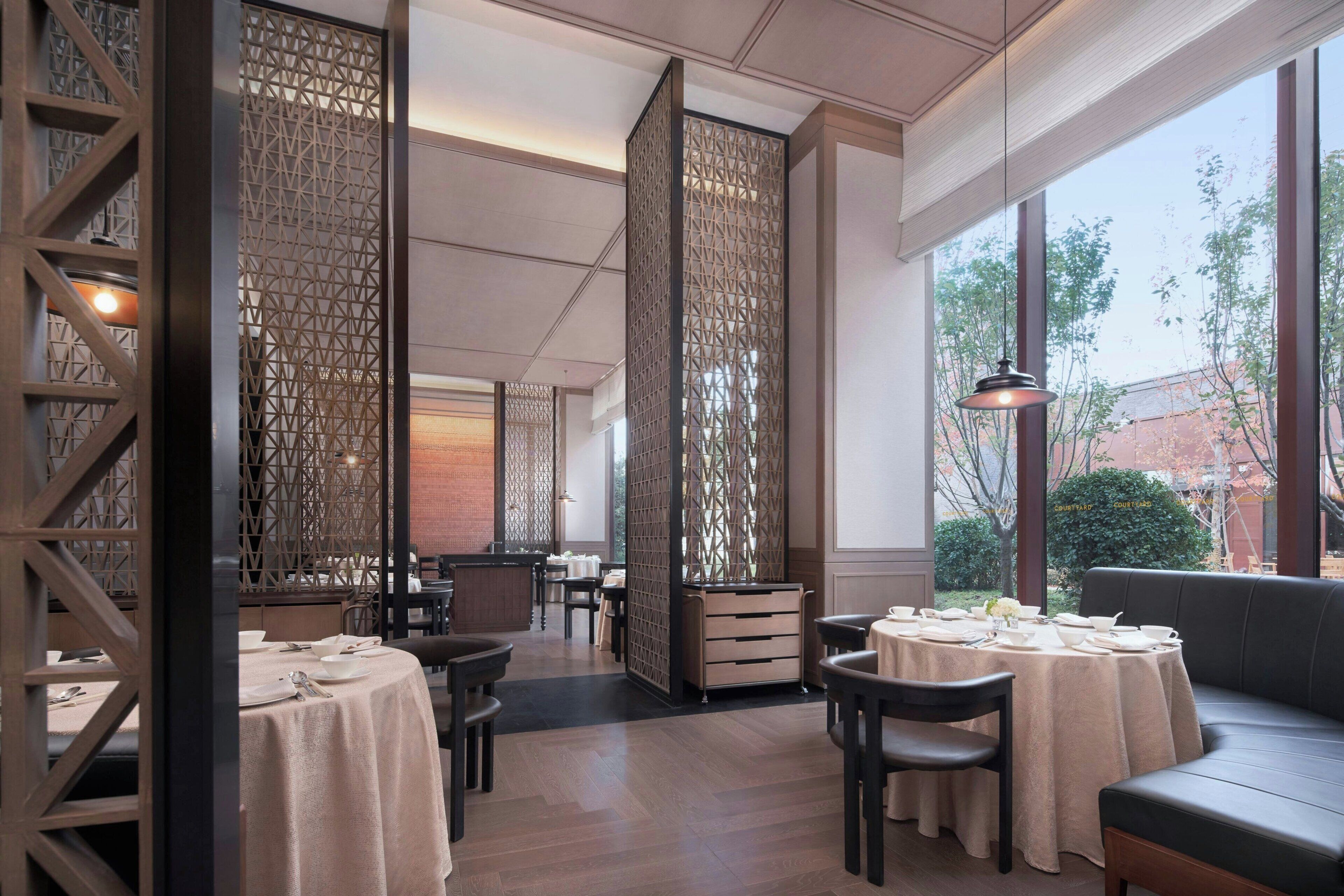 Un restaurante con mesas preparadas para comer, un sofá y vistas a través de amplios ventanales.