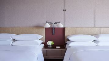 A hotel room with two beds, a nightstand with two lamps, and a vase with flowers.