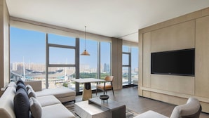 Una sala de estar moderna con un televisor grande, asientos cómodos, un comedor y vistas a la ciudad.