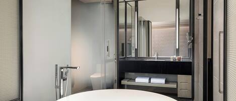 A modern bathroom with a large oval sink, a glass shower enclosure, and a dark countertop with a mirror above it.