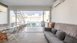 Un espacio habitable moderno con mesa de vidrio, sofá y vista panorámica de la ciudad a través de amplias ventanas.