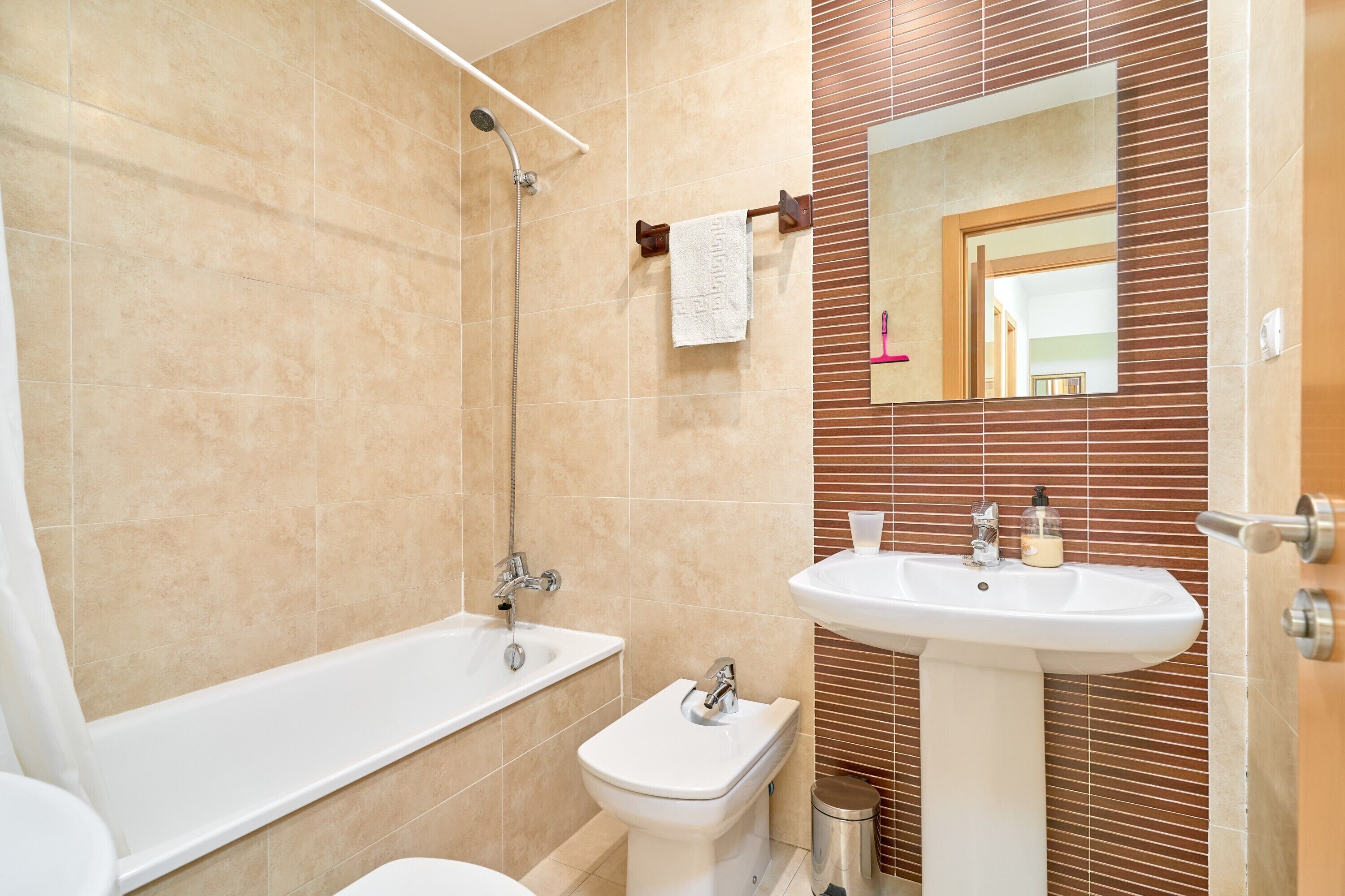 A bathroom with a bathtub, toilet, sink, and a mirror.