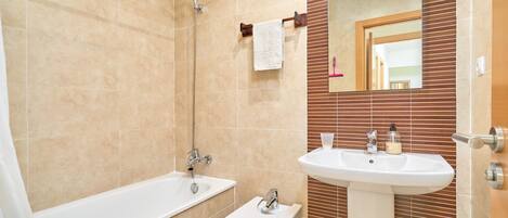 A bathroom with a bathtub, toilet, sink, and a mirror.