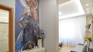 Ett modernt vardagsrum med en stor tavla, en soffa, en fiol och en vas med blommor.