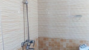 A bathroom with a shower, a sink, and a blue mat on the floor. - Muroy Executive Lodge (Kitwe)