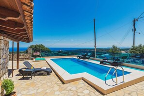 A swimming pool with lounge chairs and a stone patio. - Chania Poolside Resort - Panoramic Seaview Lodging (Platanias)