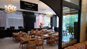 Uma área de bar com mesinhas e cadeiras, uma televisão e um aviso indicando que é exclusivo para clientes.