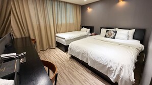 Quarto de hotel com duas camas, uma mesa, uma cadeira e uma televisão.