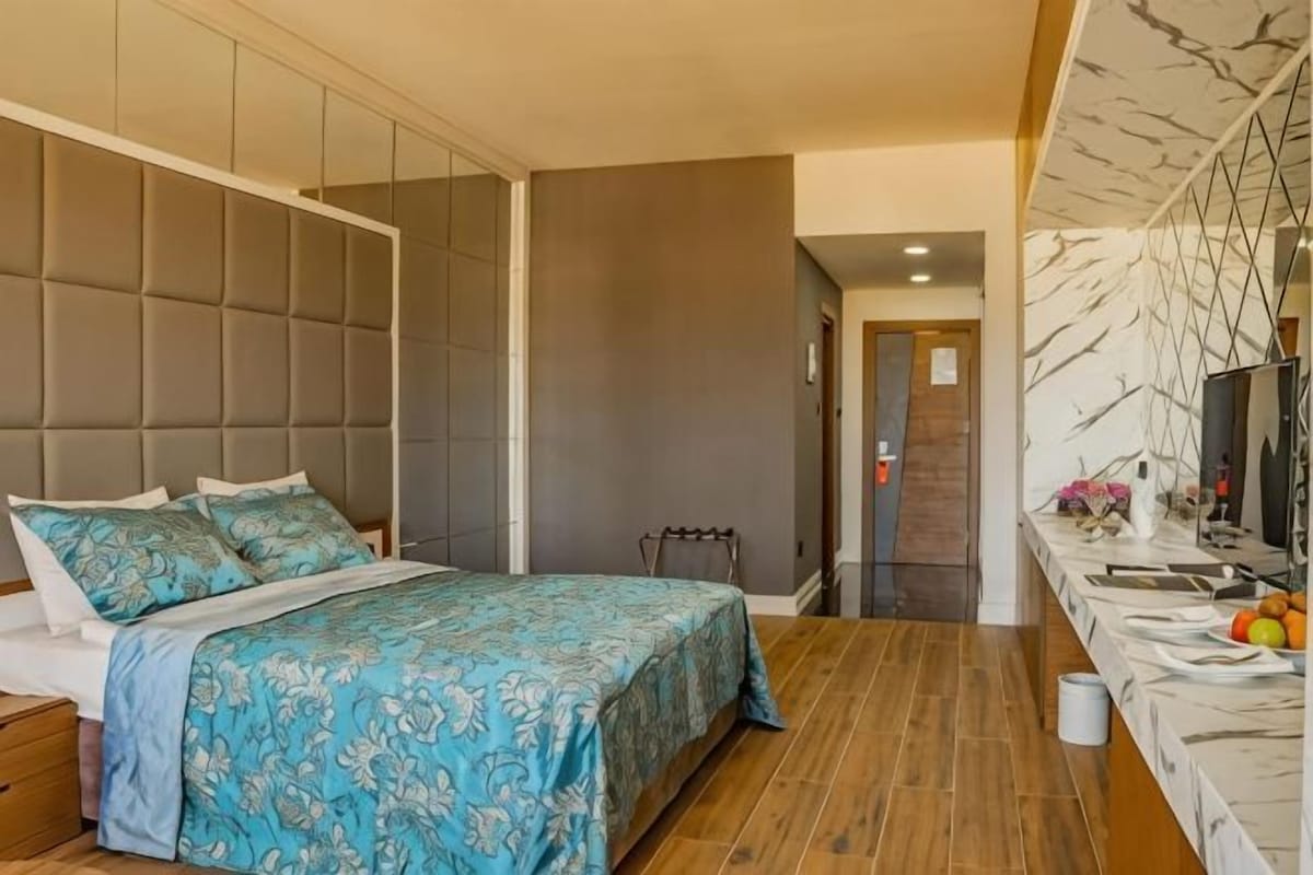 A bedroom with a bed, bedside table, and a bathroom with a sink and mirror.