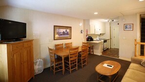 A compact living space with a dining area, kitchenette, and a television.