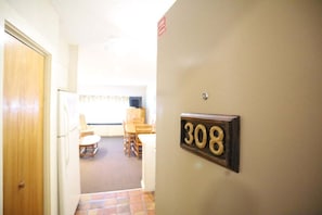 A hallway with a door on the left and a number sign '308' on the wall.