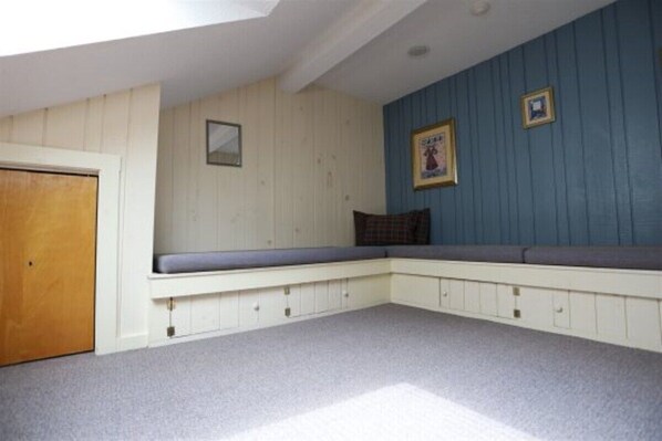A room with a built-in bench, a door, and a wall with two framed pictures.