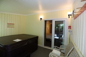 A spa room with a hot tub, a bench, and a sliding glass door leading to a balcony. - Garden Level Inns Of Waterville Valley Unit (Waterville Valley)