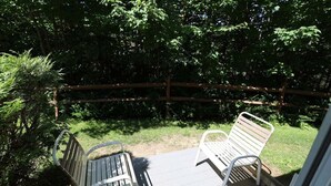 En træterrasse med to metalstole og et træhegn i baggrunden.