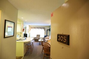 A room with a kitchen area, dining space, and a number '305' on the wall.