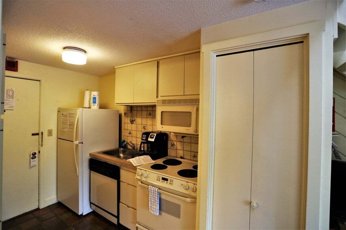 A compact kitchen with a refrigerator, stove, microwave, and a coffee maker.