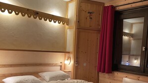Ett sovrum med en sänggavel i trä, en stor säng med många kuddar, ett nattduksbord med en lampa och ett fönster med gardiner.