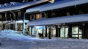 En snötäckt gata med byggnader och en skylt som visar texten ”Hotel de France”.