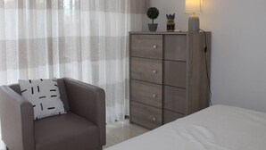 A bedroom with a bed, a chair, a wardrobe, and a lamp. - Ground Floor 3-Room Apartment with Terrace & Garden, 5 min to Beach, A/C, Parking, Villeneuve-Loubet (Villeneuve-Loubet)